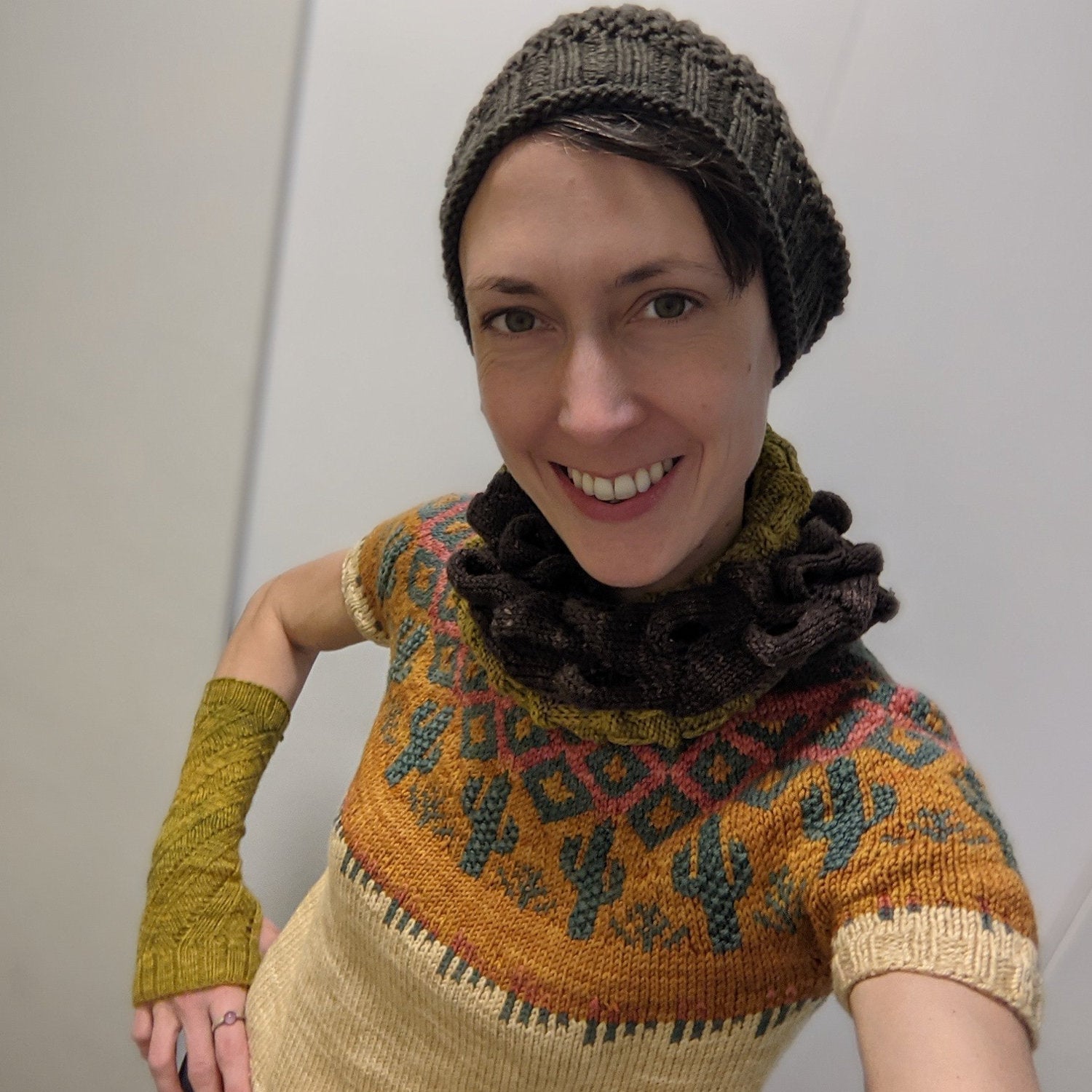 Woman wearing hand knitted hat, cowl, sweater and wristwarmers