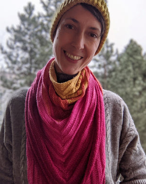 Person wearing a hat, smiling and a shawl draped around their neck