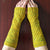 Two arms wearing a pair of naturally dyed gold green wristwarmers