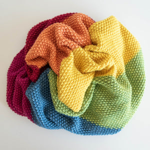 Naturally dyed baby blanket in colours of the rainbow scrunched up in a circle