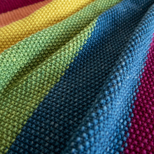 Close up of seed stitch baby blanket in naturally dyed yarn in rainbow colours 